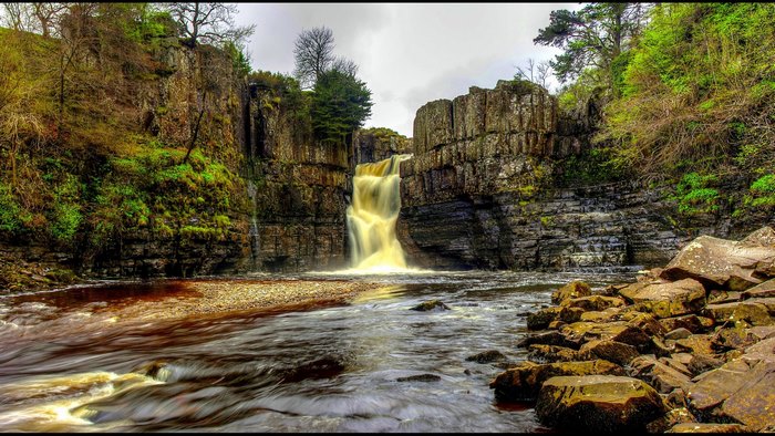 Waterfall cascading over rocky cliffs into a river