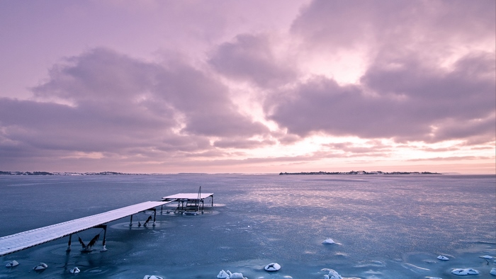 Frozen lake with a snow-covered pier under a cloudy sky