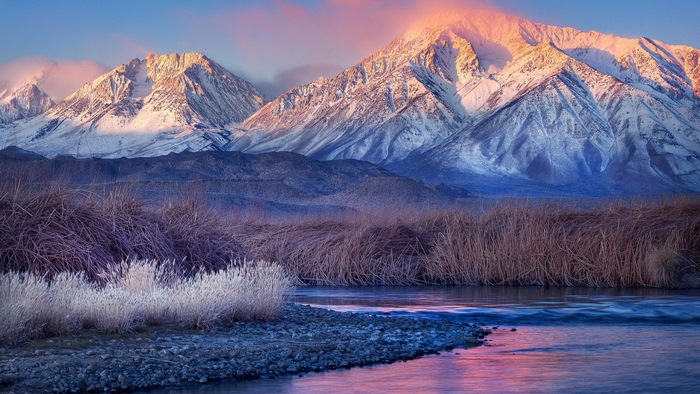 Snow-capped mountains at sunrise with a river