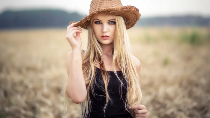 Blonde Woman in Black Dress with Straw Hat in Field