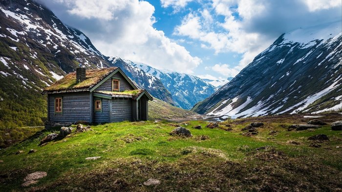 Wooden cabin with grass roof in snowy mountains