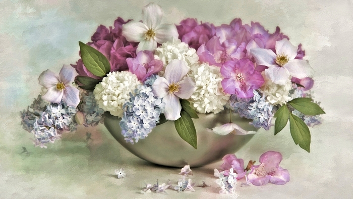 A silver bowl filled with a variety of colorful flowers