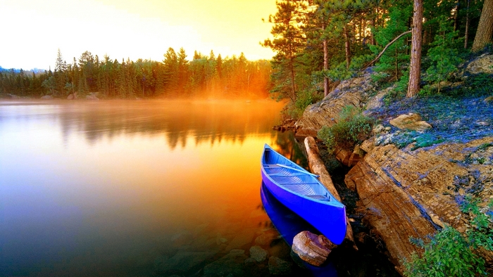 Blue canoe on a misty lake at sunset