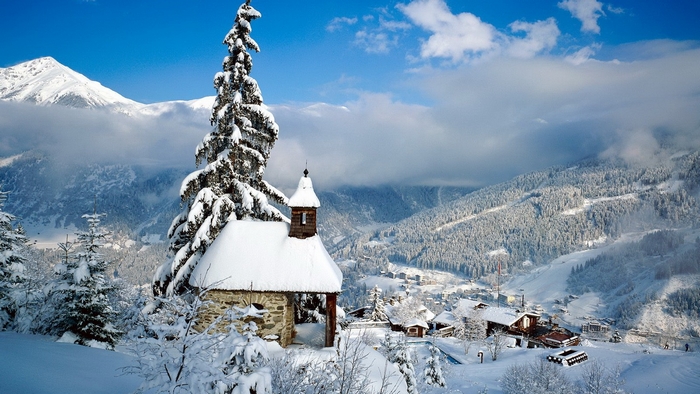 Snowy mountain landscape with a small chapel and pine tree