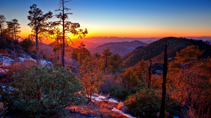 Sunset over mountains with trees and hills