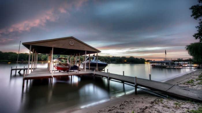 Boats docked at a covered pier on a lake at sunset