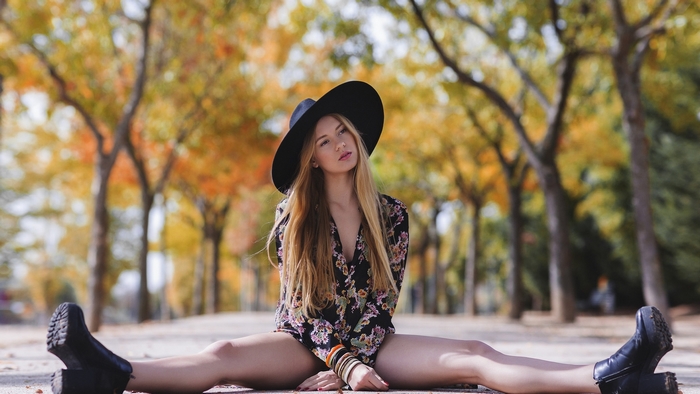 Woman in Black Floral Shirt and Wide-Brim Hat Sitting Outdoors