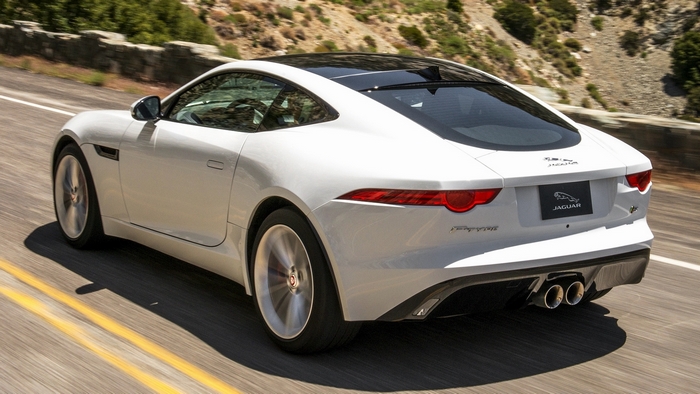 White Jaguar F-Type Coupe driving on a mountain road