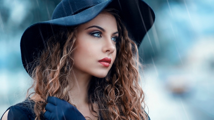 Woman in a black hat with curly hair in the rain