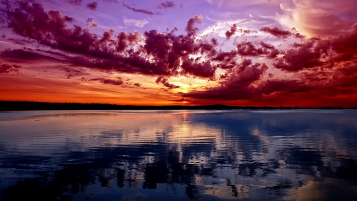 Sunset over a calm lake with dramatic clouds
