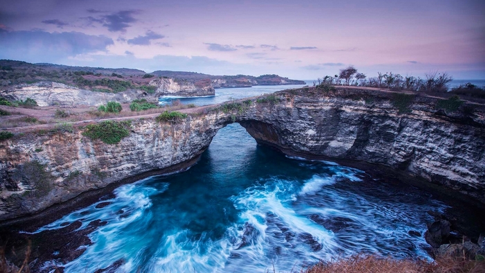 Natural rock arch over the ocean at twilight