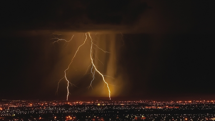 Lightning strikes over a city at night
