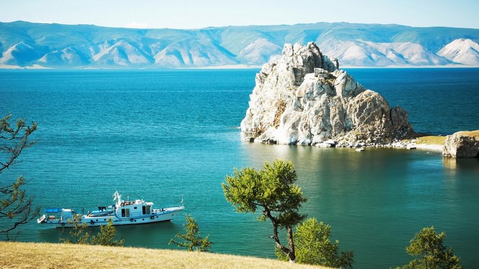 Boat on a lake with rocky island and mountains in Russia