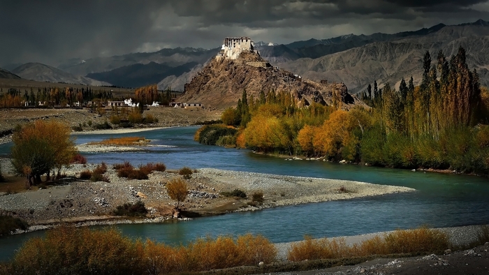 River flowing through a valley with a monastery on a hill