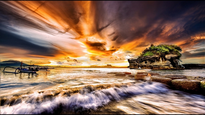 Ocean sunset with temple on rock island and boats