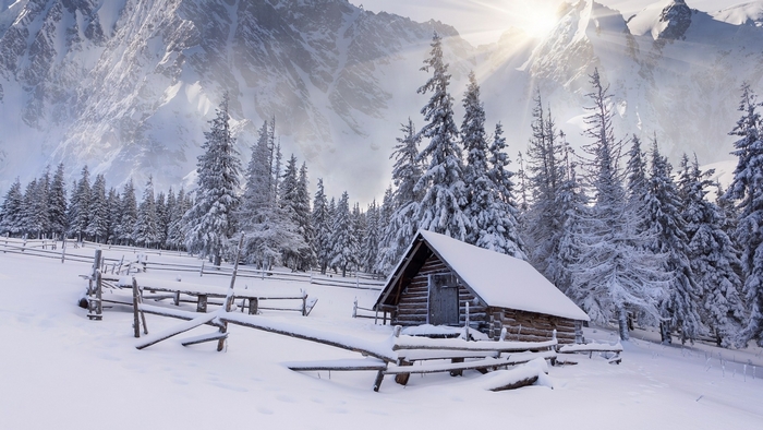 Snowy mountains with a small wooden cabin and fence