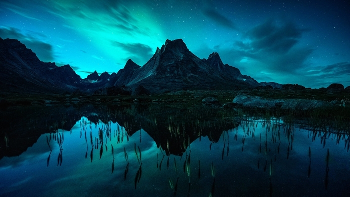 Aurora Borealis over mountains reflected in a lake