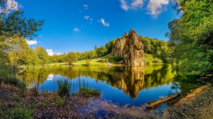 Rock formation reflected in a lake with trees and sky