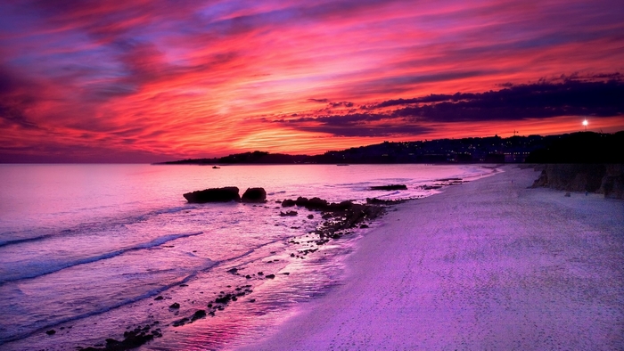 Beach sunset with vibrant pink and purple sky over the ocean