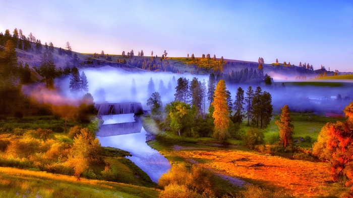 Misty river and bridge at dawn with rolling hills