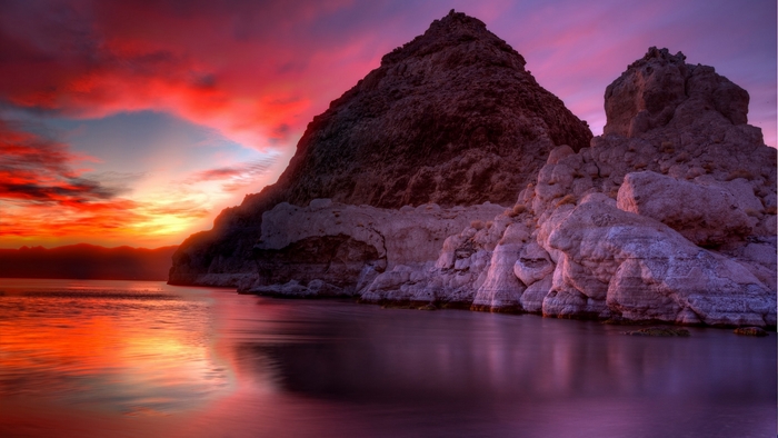Rocky shore at sunset with vibrant sky reflection