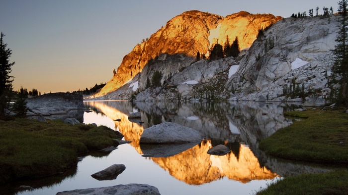 Mountain lake reflecting golden sunlight at sunset