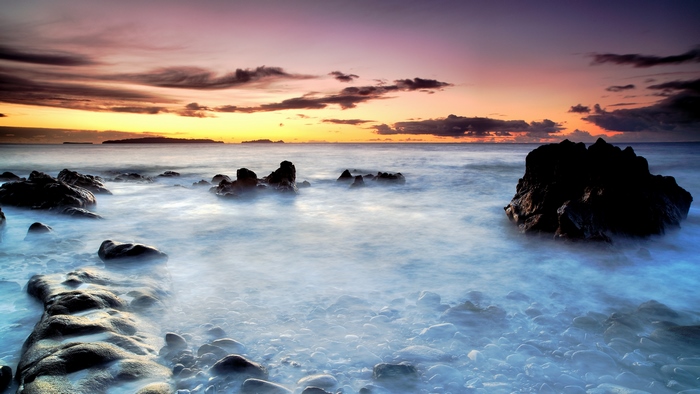 Misty sunset over rocky ocean shore