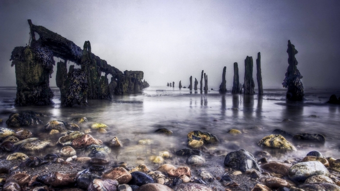 Ocean beach with weathered wooden posts and rocks