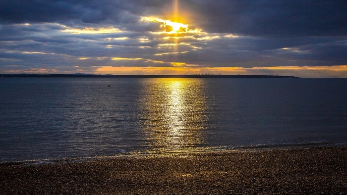 Sunset over the ocean with a pebble beach