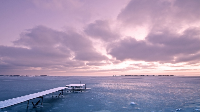Frozen pier on a calm winter ocean at sunset
