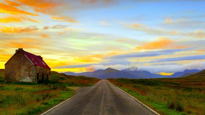 Abandoned house on a road at sunset