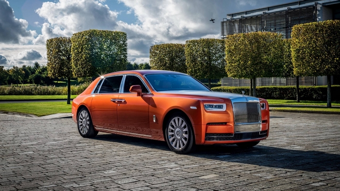 Orange Rolls-Royce Phantom parked on cobblestone