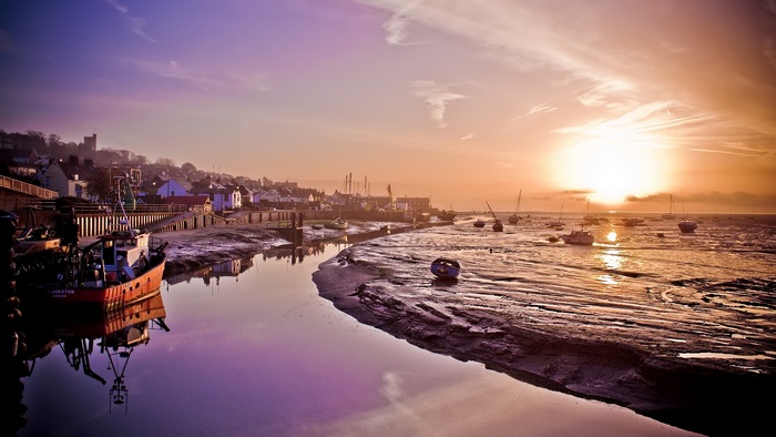 Boats at low tide during sunrise in a coastal village