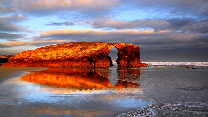 Rock arch on a beach at sunset