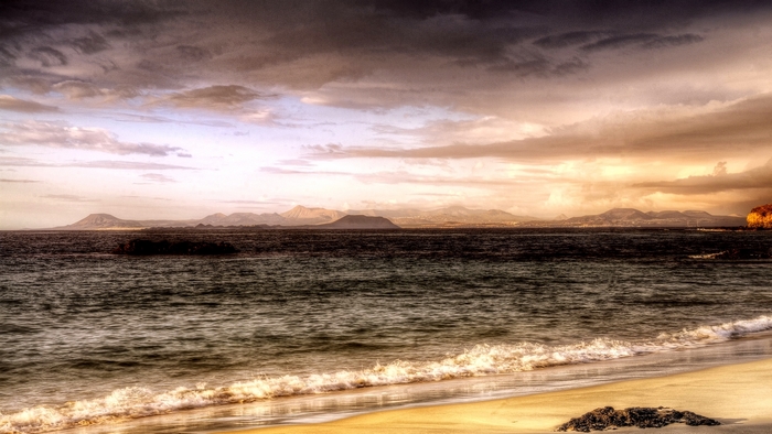 Beach with mountains and stormy sky