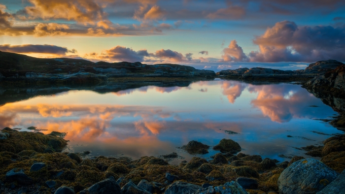 Sunset over rocky coast with reflections