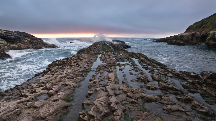 Rocky coastline with waves crashing at sunset