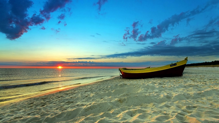 Boat on a sandy beach at sunset