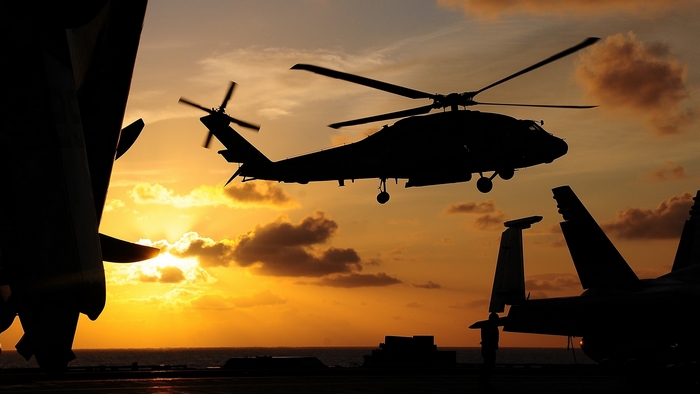 Helicopter and fighter jets on aircraft carrier at sunset
