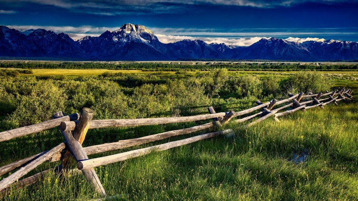 Wooden fence in front of mountains and fields