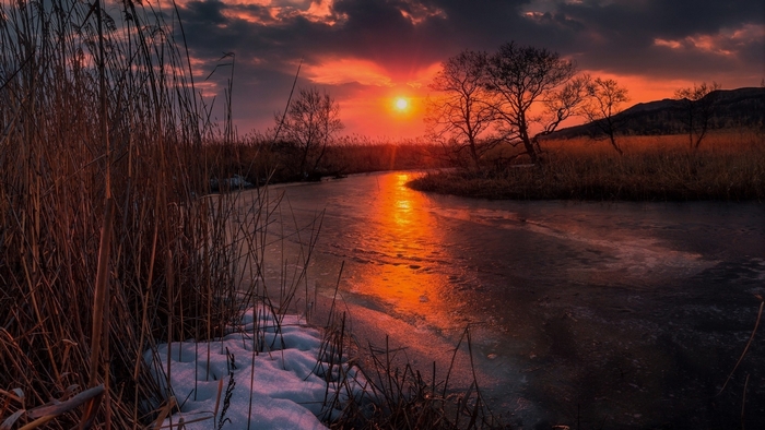 Sunset Over Frozen River with Snow and Trees