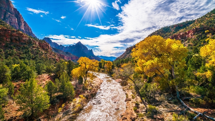 Sunlit Autumn River Flowing Through Mountains