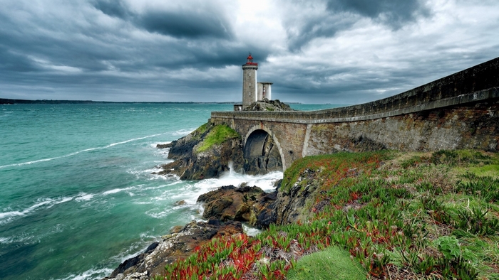 Lighthouse on a rocky coast with a stone bridge