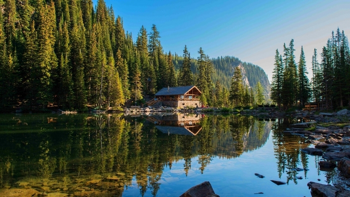Log cabin by a lake surrounded by a forest