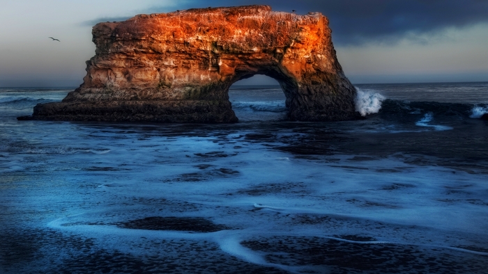 Natural Bridges State Beach arch rock formation at sunset