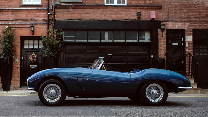 Blue Aston Martin sports car parked outside brick building