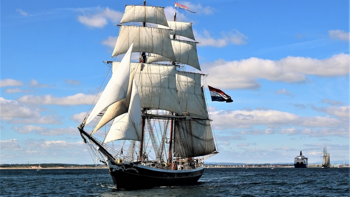 Tall ship sailing on the ocean with flags