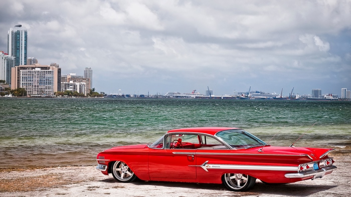 Red Chevy Car by Waterfront in Cityscape