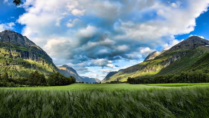 Green valley with mountains and clouds