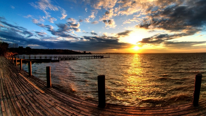 Wooden pier at sunset over the sea with clouds
